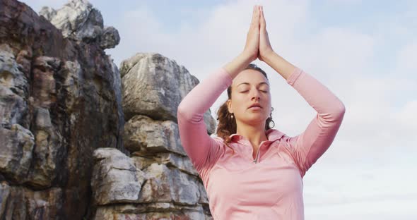 Caucasian woman practicing yoga meditation outdoors in rural mountainside setting alt