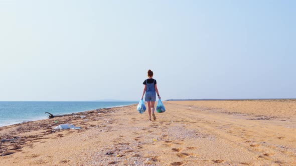 A Volunteer Is Collecting Plastic Garbage on a Beach alt