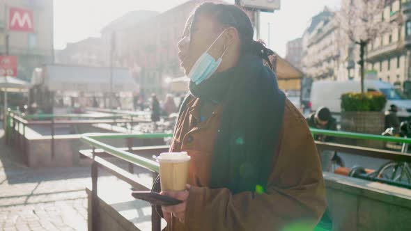 Young woman with face mask using smart phone outdoors, Italy