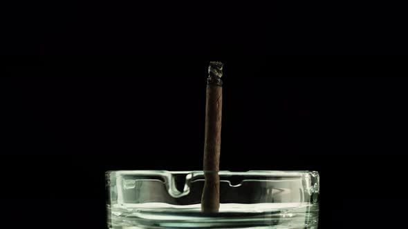 Cigar In An Ashtray With Smoke On A Black Background, A Cigarette Smolders With A Copy Space.