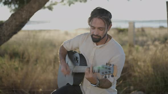 Handsome Man Guitarist Strumming on Classic Acoustic Guitar and Singing Song Looking at Camera Lens alt