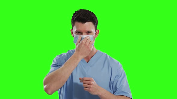 Caucasian male doctor wearing face mask on green screen background alt