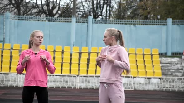 Young Caucasian Identical Twins in Sportswear Stretching Their Bodies at Stadium