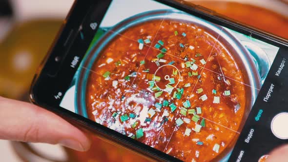 Female Hands Taking a Picture on a Smartphone Traditional Ukrainian Red Borscht alt