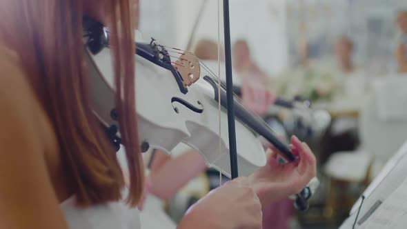 Woman in White Dress Plays on White Violin