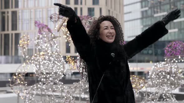 A Curlyhaired Stylish Middleaged Brunette Woman in a Black Fur Coat Walks Alone in the City on a alt
