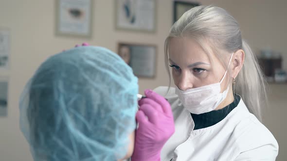 Blonde Woman Makes Brow Tattooing on Client Face in Clinic alt
