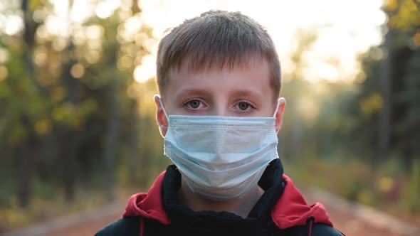 Portrait of Little Boy Wearing Medical Mask on Autumn Park