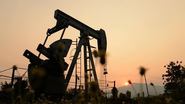pumpjack at an oil drilling site and sunset