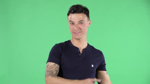 Portrait of a Handsome Young Guy Is Looking at Camera and Pointing Side Hand for Something Then alt