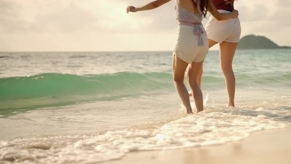 Two Asian girl friends are having fun on the beach while on vacation. concept of freedom
