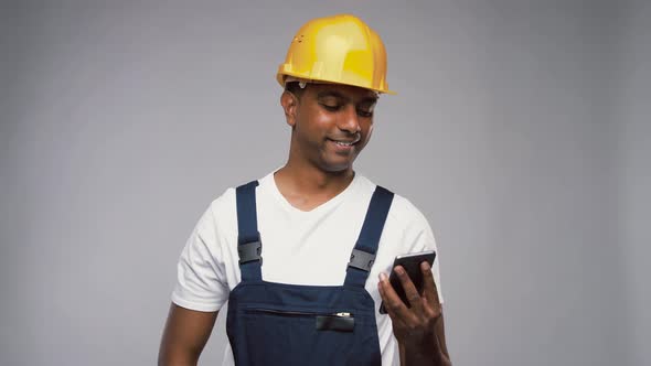 Indian Builder in Helmet Calling on Smartphone alt