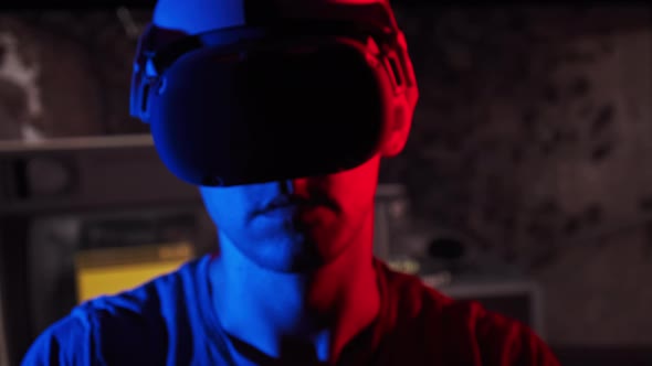 Man in a Virtual Reality Helmet Illuminated in Red and Blue Plays a Game alt