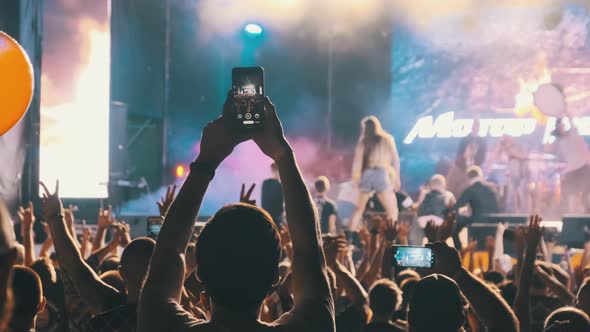 Male with Smartphone in Hand Making Video at Live Rock Concert. Slow Motion alt