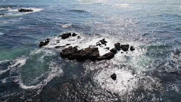 Circle Aerial View Waves Break on Rocks in a Blue Ocean