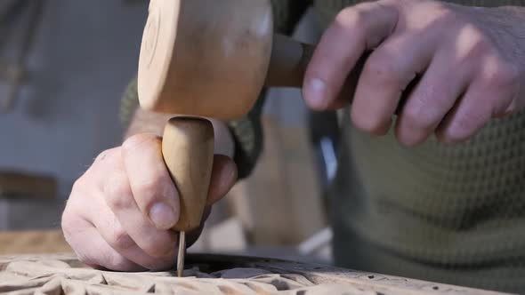 the Male Hands of a Craftsman of Artistic Wood Carving Holding an Awl Knock on It with a Wooden