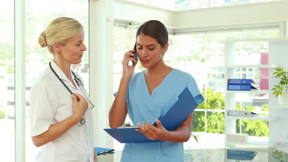 Doctors Holding Clipboard and Having a Phone Call alt