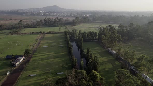 Aerial shot of football soccer fields with lake, sunrise