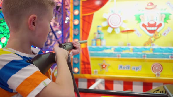 Boy is Shooting at Targets Ducks with Gun in a Shooting Simulator at Children's Entertainment Center