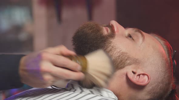 Handsome Man on Chair of Barber Having Procedure of Shaving. alt