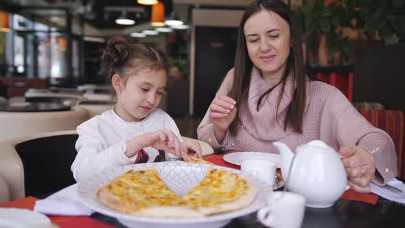 Woman with Little Daughter in a Restaurant Eat Only Cooked Cheese Pizza
