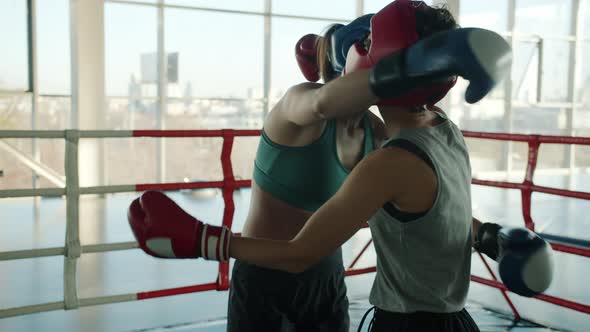 Slow Motion of Beautiful Young Women Wearing Helmets and Gloves Hugging After Match in Modern Gym alt