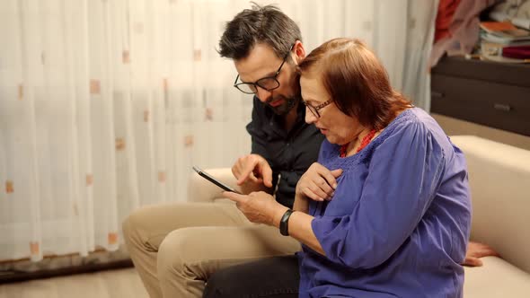 Grandmather With Grandson Using Mobile Phone.Grandson Teaching Grandma Using Mobile Phone Camera. alt