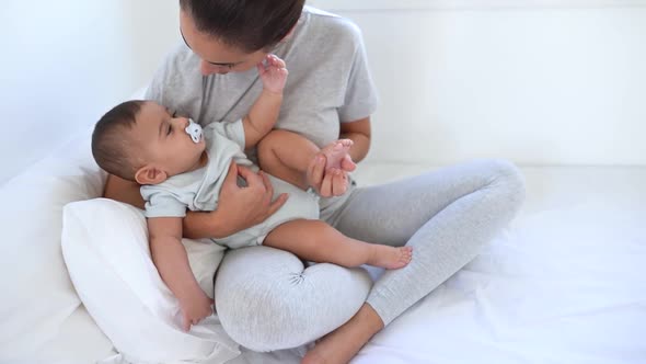 Happy mother having fun with her little baby on bed - Family and maternity concept alt