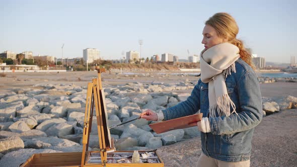 Side View Portrait of Young Talented Woman Painter Creating Picture on River Bank in City Tracking alt