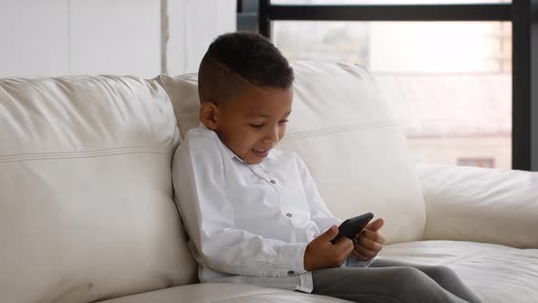 Excited Black Preteen Boy Playing Video Games On Smartphone At Home ...