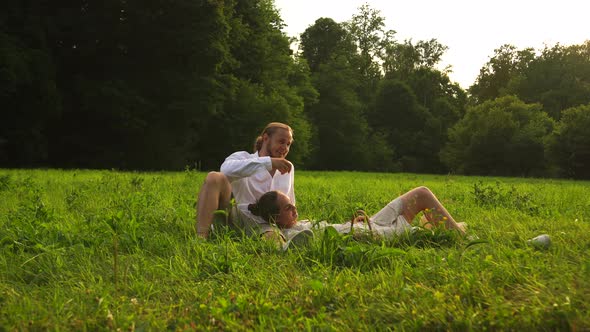 Man Woman Resting in Nature Among the Grass Forest While Sitting on Blanket alt