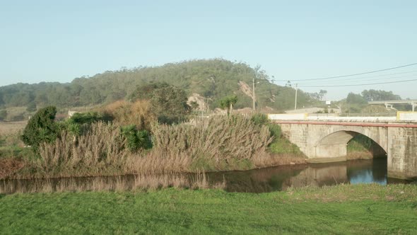Car Traveling Across Stone Arch Bridge Over Calm Lake Of Alcobaca River Near Nazare In Portugal. - A alt