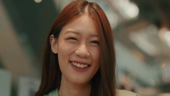 Young Attractive Asian Woman wearing casual clothes looking at the camera and smiling