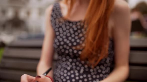 Cute Teen Caucasian Redhead Girl in Black Polka Dot Dress Reading Notes While Wind Blowing Hair on alt