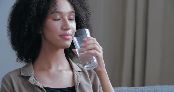 Close Up of Young African American Woman Quenches Her Thirst, Holds Glass Cool Warm Water, Drinks alt