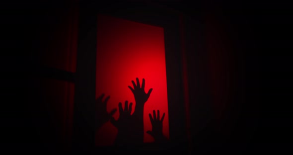 Creepy hands drag down a window in distress