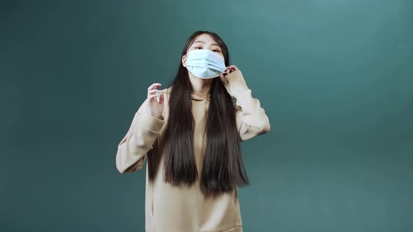 An Attractive Cheerful Asian Lady is Putting on Medical Mask for Health Protection and Prevention