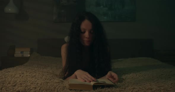 Woman Opening A Book In A Dimly Lit Room