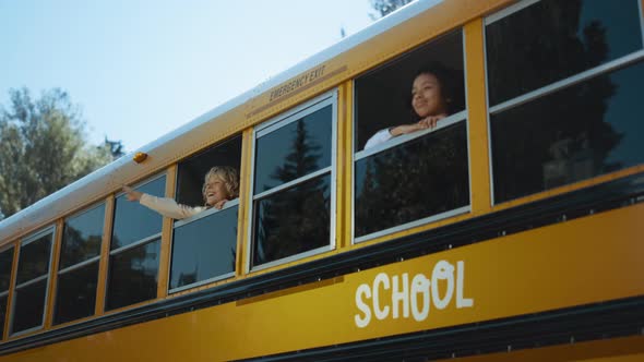 Two Multiethnic Pupils Looking Out School Bus Window alt
