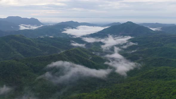 Aerial view of sunrise above fluffy sea fog misty clouds with mountain hill alt