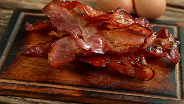 Super Slow Motion Shot of Roasted Bacon Slices Falling on Wooden Board at 1000 Fps alt