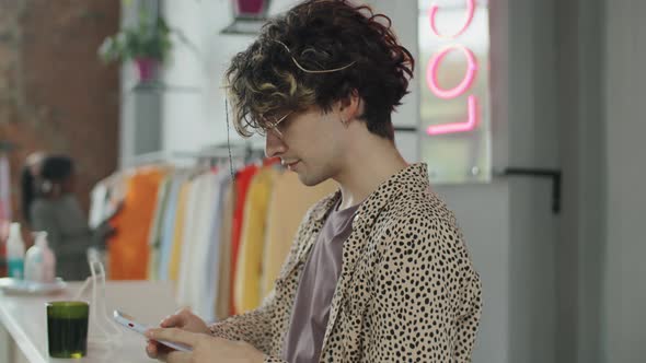Young Man Using Smartphone in Clothes Shop alt