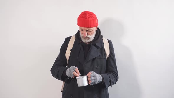Portrait of Homeless Beggar with Cup for Money Finds Large Bill in His Cup alt