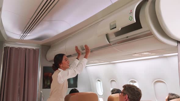 A stewardess closes the cabin overhead on aircraft.