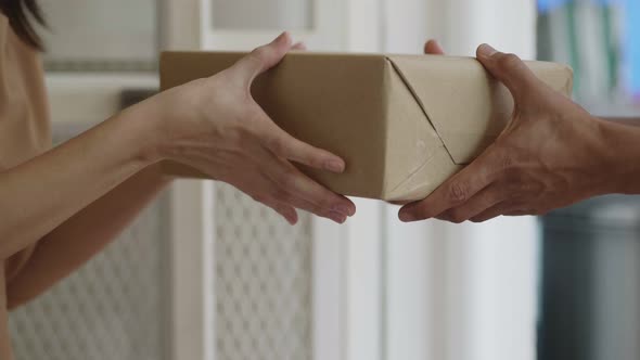 Close up hands Asian woman receive a cardboard box from a man's delivery holding at home.