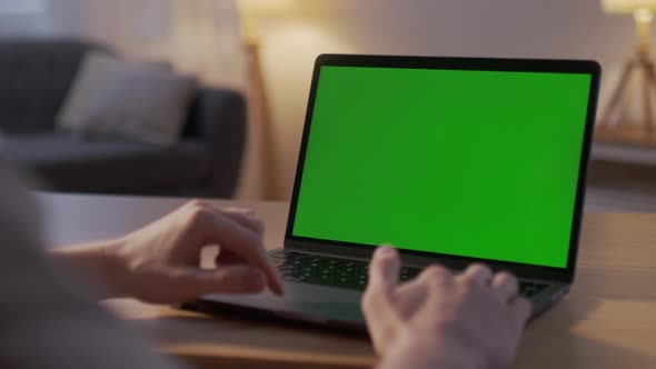 Closeup On the Hands of the Male Specialist Works on a Laptop Computer with Mockup Green Screen