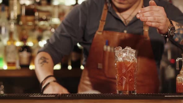 Close Up Shot of the Man's Hands He Puts the Ice in Vegetable Juice for Visitor alt