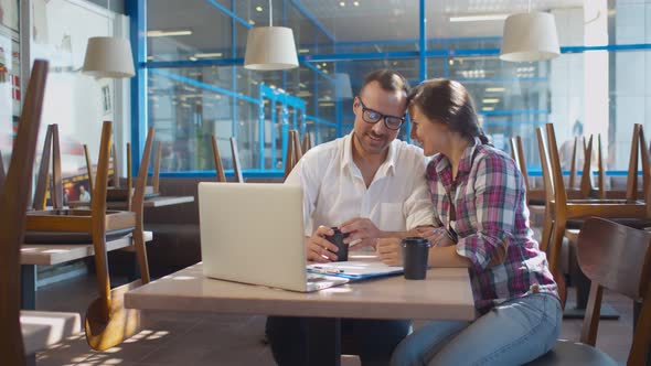 Young Happy Couple Cafe Owners Reading E-mails From Food Suppliers on Laptop Screen alt