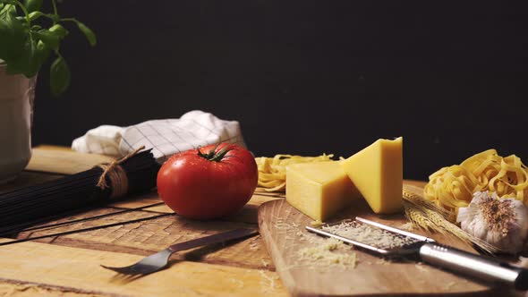 Shredded Cheese with Fresh Basil and Italian Spaghetti on Wooden Kitchen Table