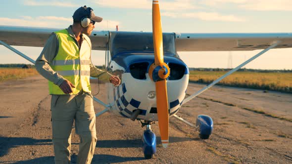 Male Aviator Walks Away From the Plane and Taking Off the Headphones alt